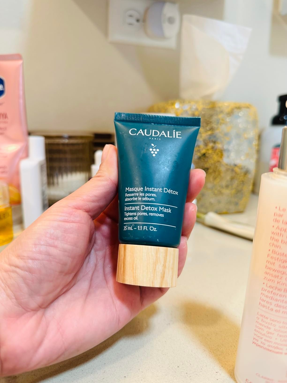 Caudalie Instant Detox Mask tube held in hand