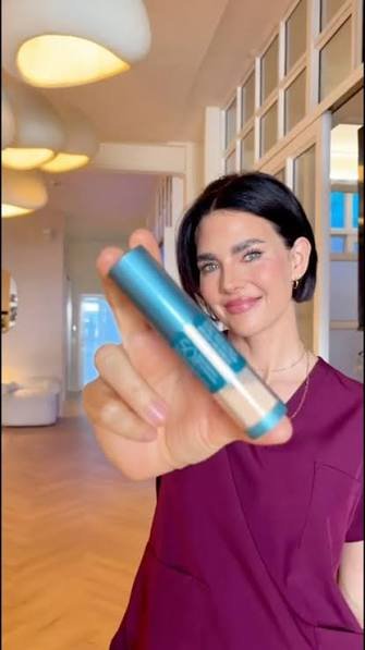 Person holding Colorescience Brush-On Shield SPF 50 near the face