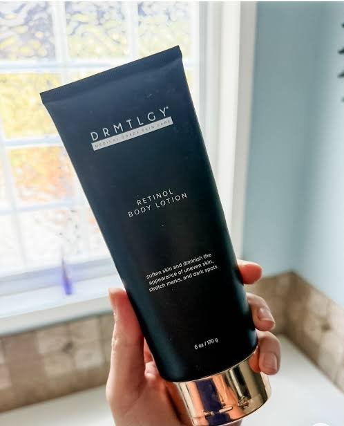 DRMTLGY Retinol Body Lotion black tube held near a window