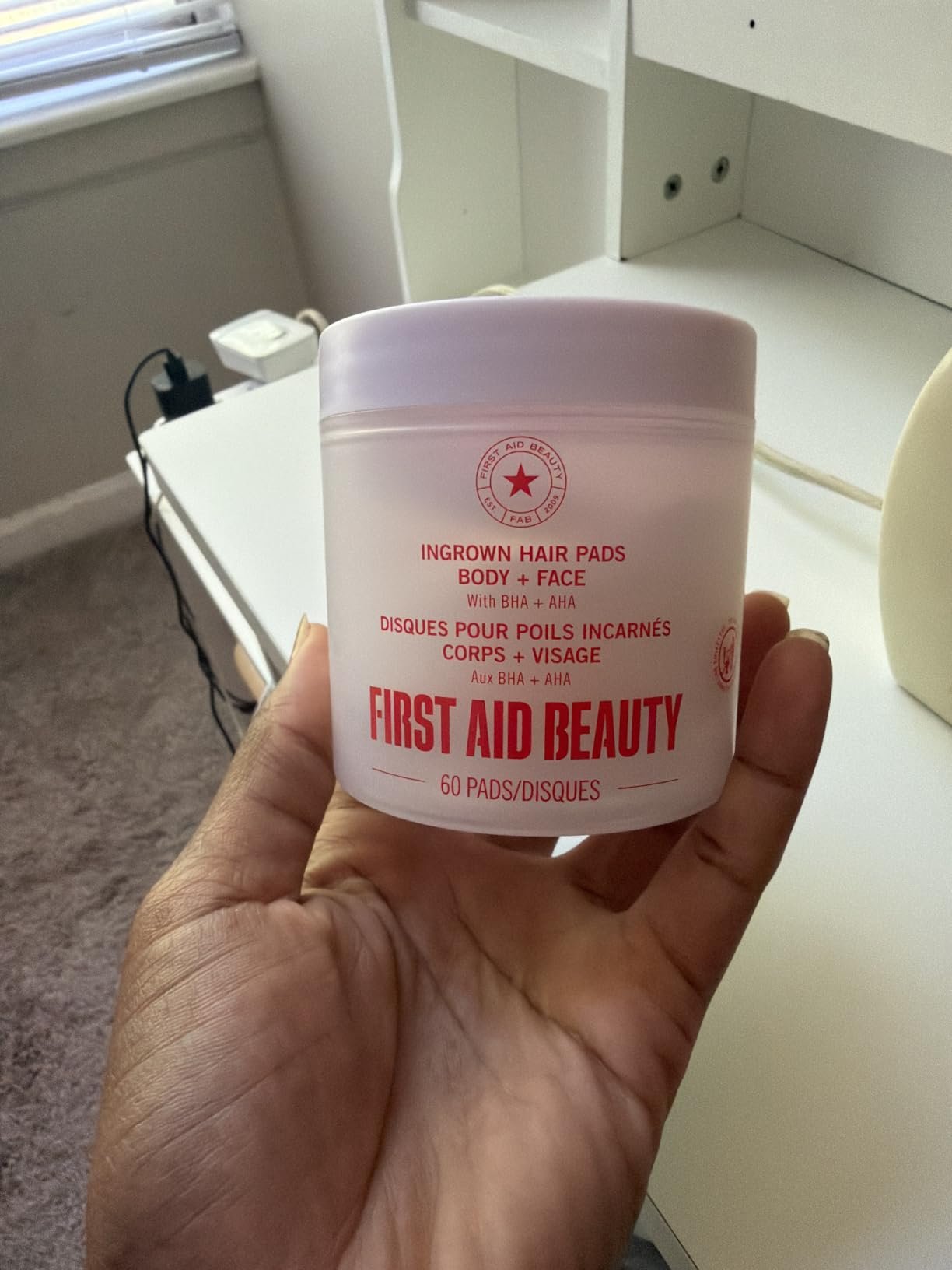First Aid Beauty Ingrown Hair Pads jar held in hand