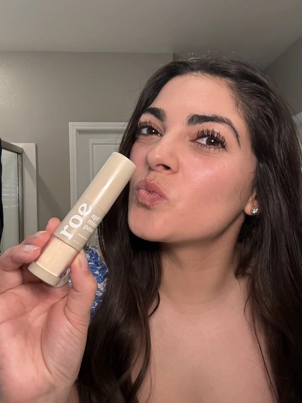 Person holding roe Wellness SPF 50 Mineral Powder beside the face